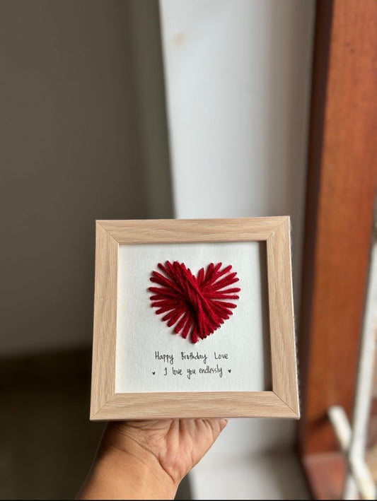 Hand holding handcrafted square frame with red heart design, romantic decorative photo frame gift