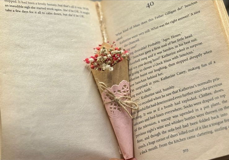 Small artificial bouquet with pink flowers wrapped in pink paper, decorative affordable gift