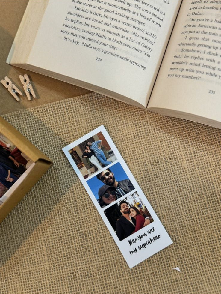 Handcrafted personalized photo strip with 3 prints placed on textured surface with book and pen